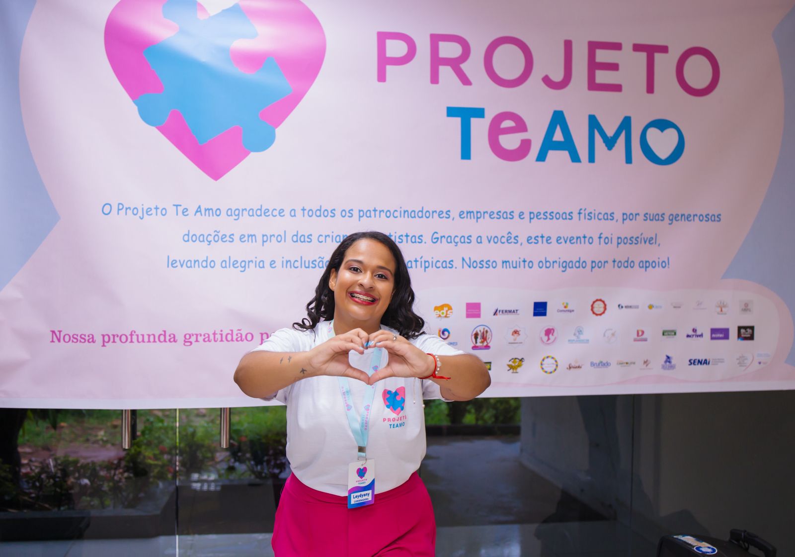 Foto da idealizadora do Projeto TEAMO em frente ao painel oficial